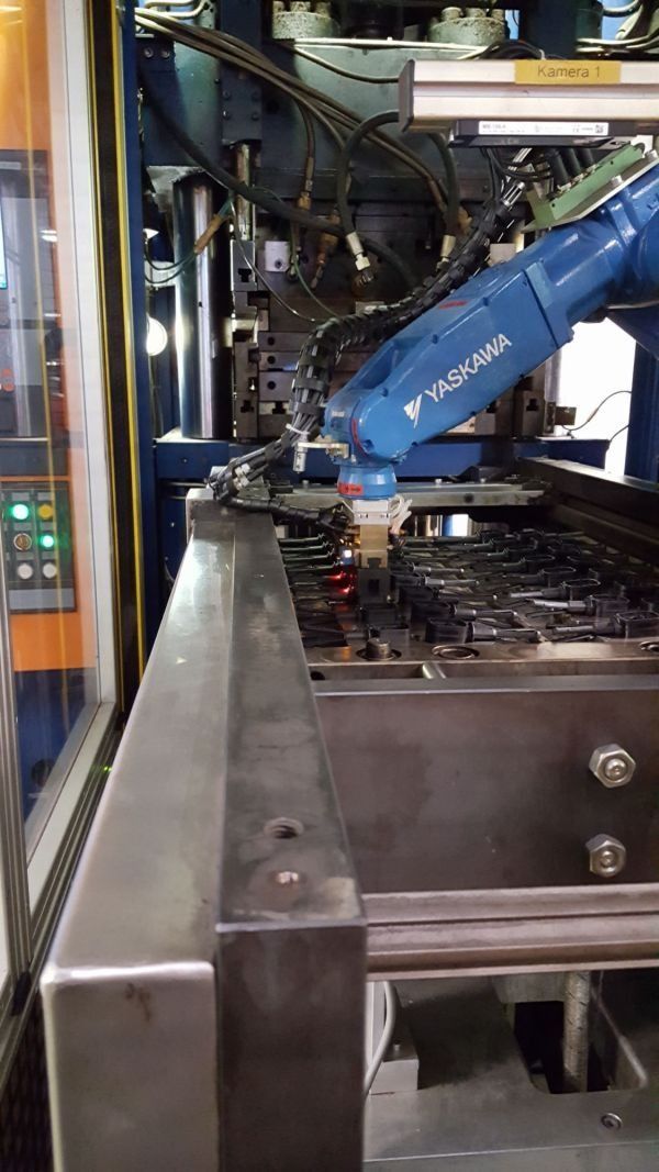Blauer Industrieroboterarm in einem Fabrikmaschinengehäuse mit Metallschienen und Kabeln