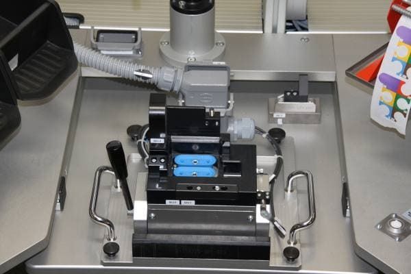 Nahaufnahme eines Laborgeräts mit blauen Proben auf einem Metalltablett und seitlichen Griffen