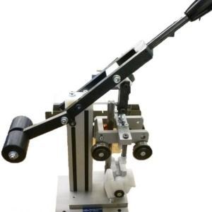 Kleines, schwarz-silbernes mechanisches Gerät mit Hebelarm und Rollen auf weißem Hintergrund