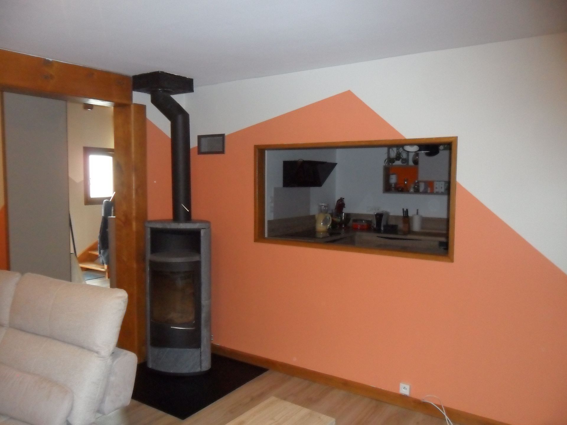 Une personne peint un mur blanc au rouleau à peinture dans une pièce, à l'aide d'une échelle.