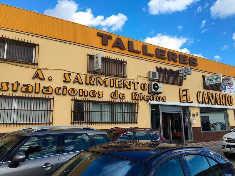 Los coches están aparcados delante de un edificio que dice talleres