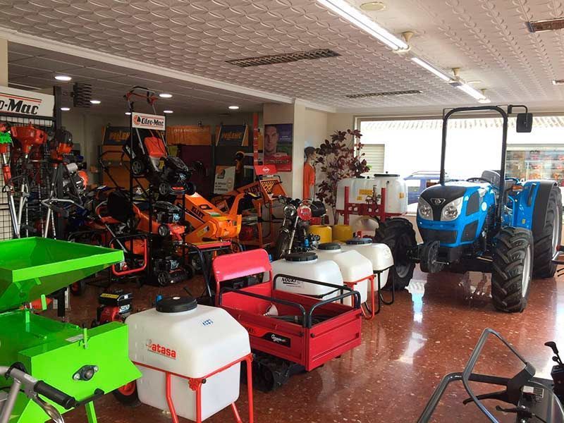 Una sala de exposición llena de una variedad de tractores y cortadoras de césped.