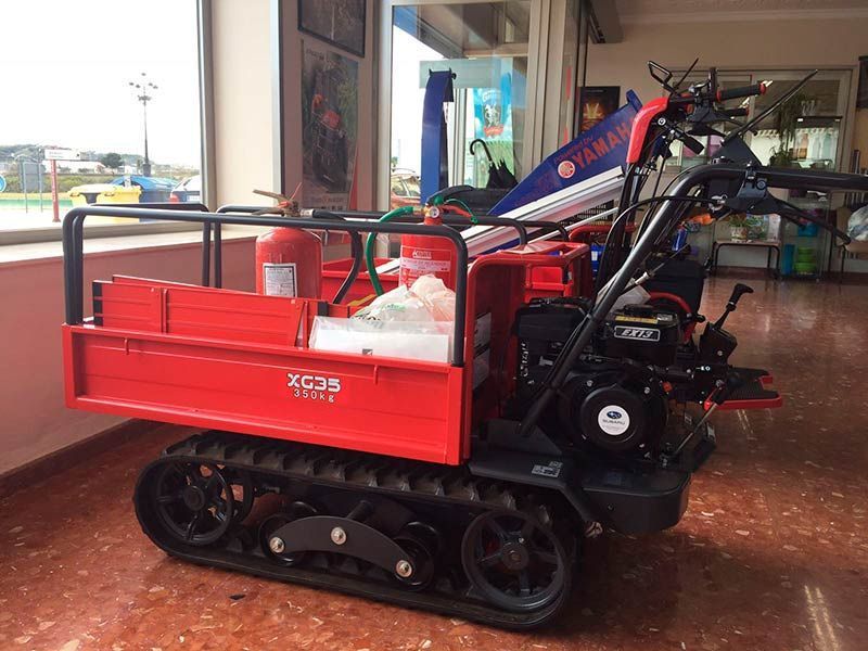 Un tractor rojo está estacionado en una habitación al lado de una ventana.