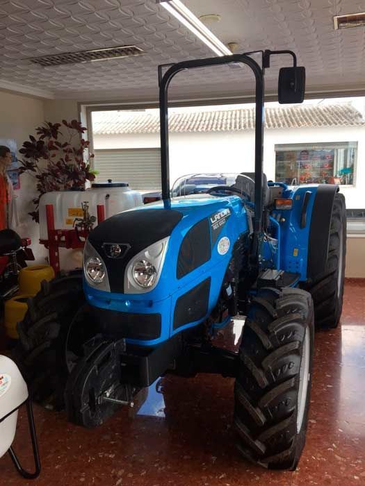 Un tractor azul está estacionado en una habitación frente a una ventana.