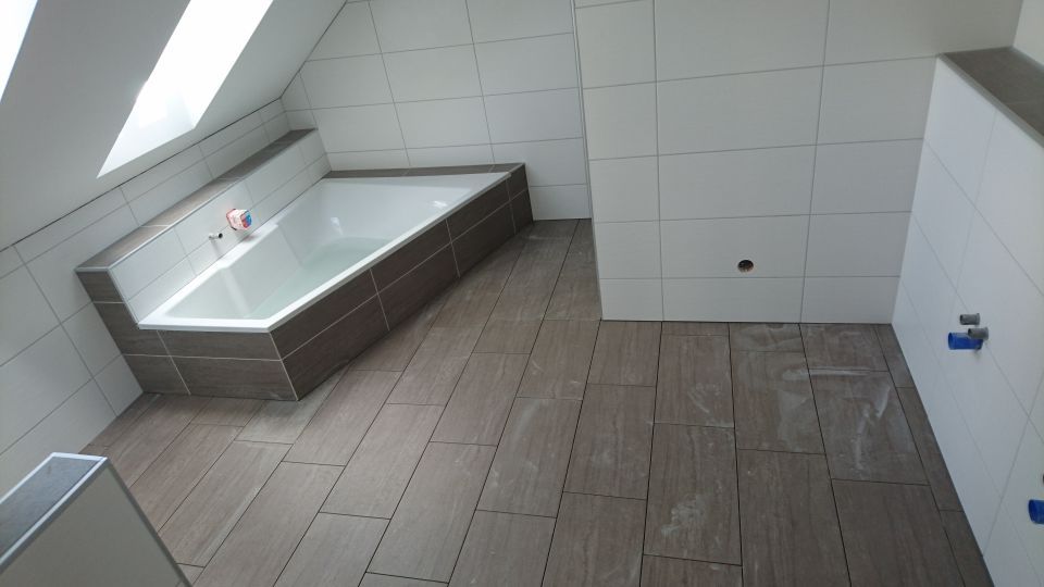 Niedrige Badewanne im neu verfliesten Bad in Braun und Grau