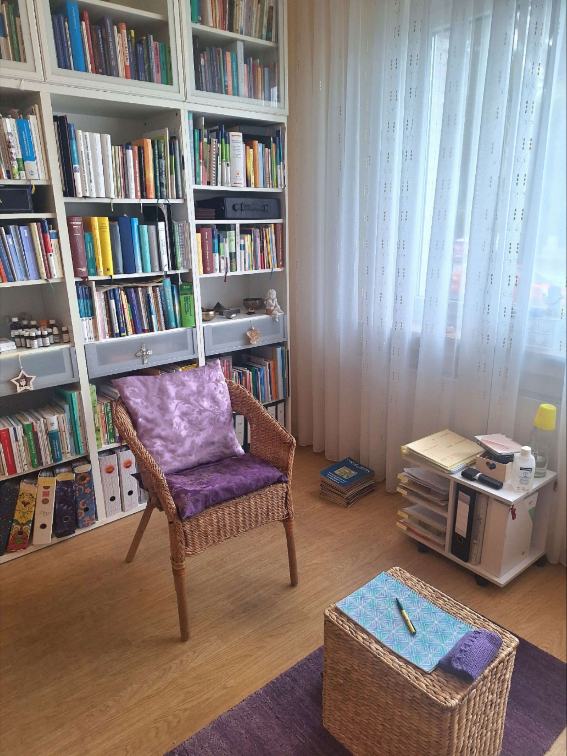 Praxiszimmer mit einem Stuhl, Tisch und großem Bücherregal
