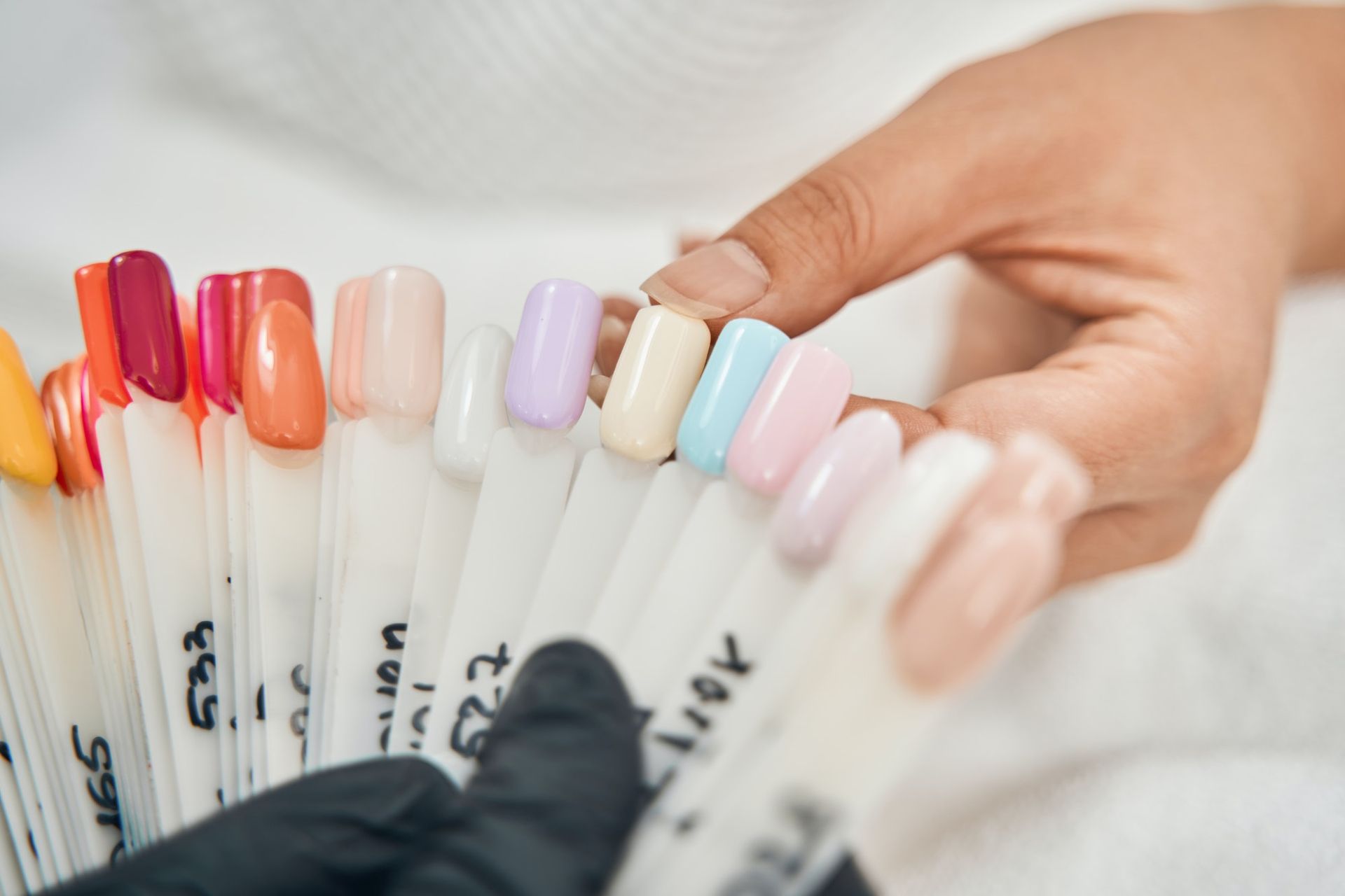 Une femme tient un tas d'échantillons de vernis à ongles.