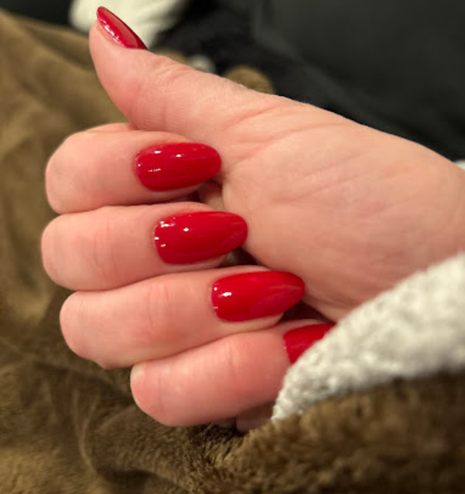 Un gros plan de la main d'une personne avec des ongles rouges