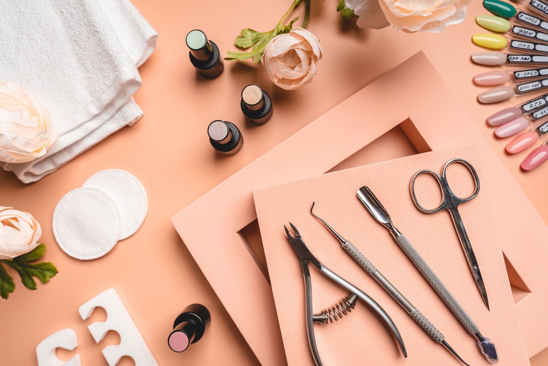 Une table sur laquelle sont posés une variété de vernis à ongles, d'outils et de fleurs.