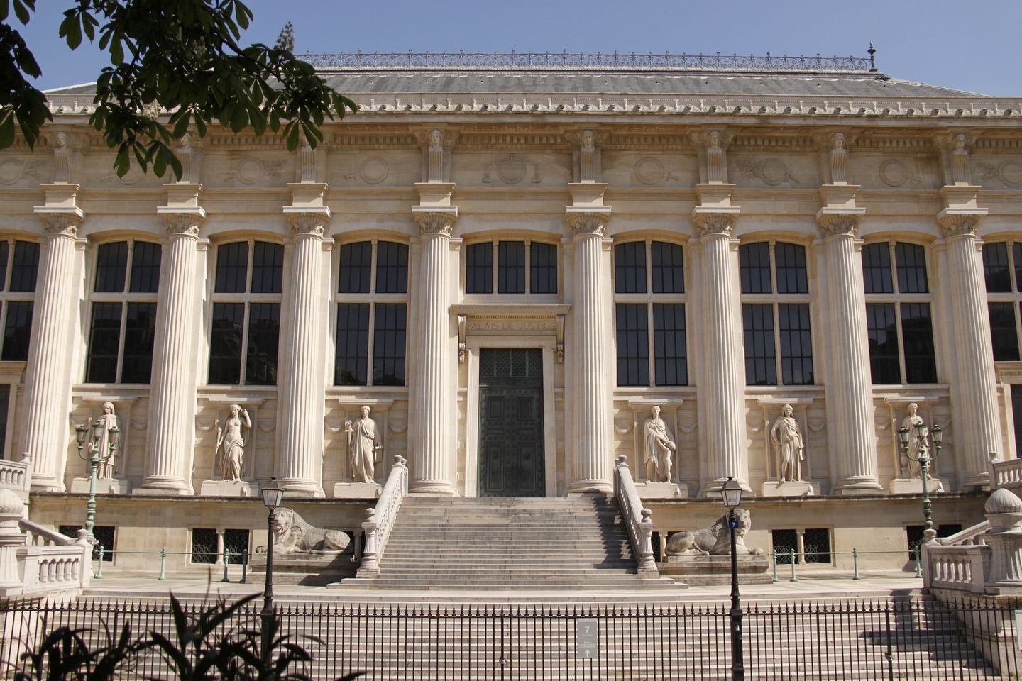 Grand bâtiment néoclassique avec de hautes colonnes blanches, un escalier central et une grille en fer forgé à l'avant
