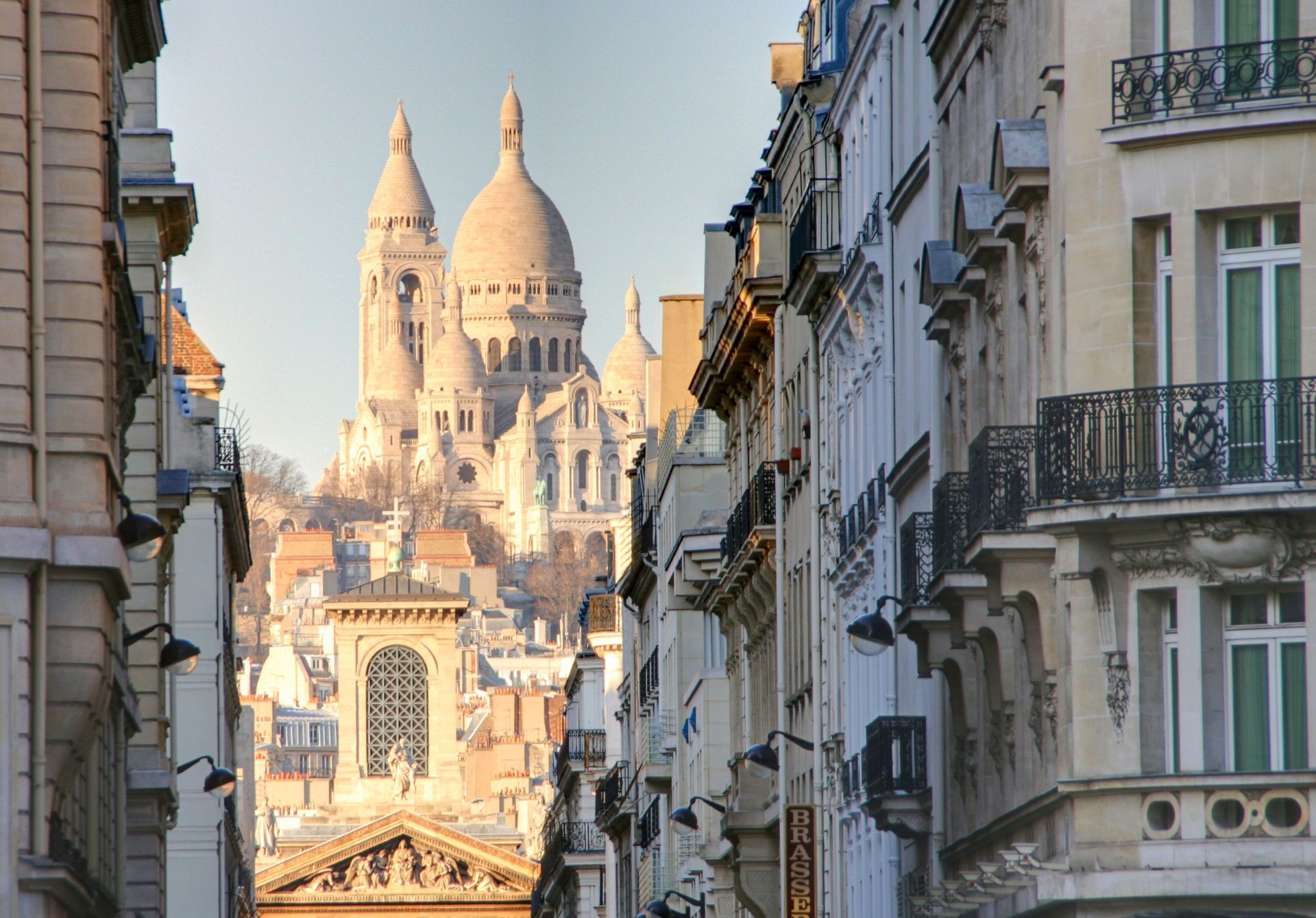Vue d'une rue parisienne sur la basilique du Sacré-Cœur illuminée au coucher du soleil