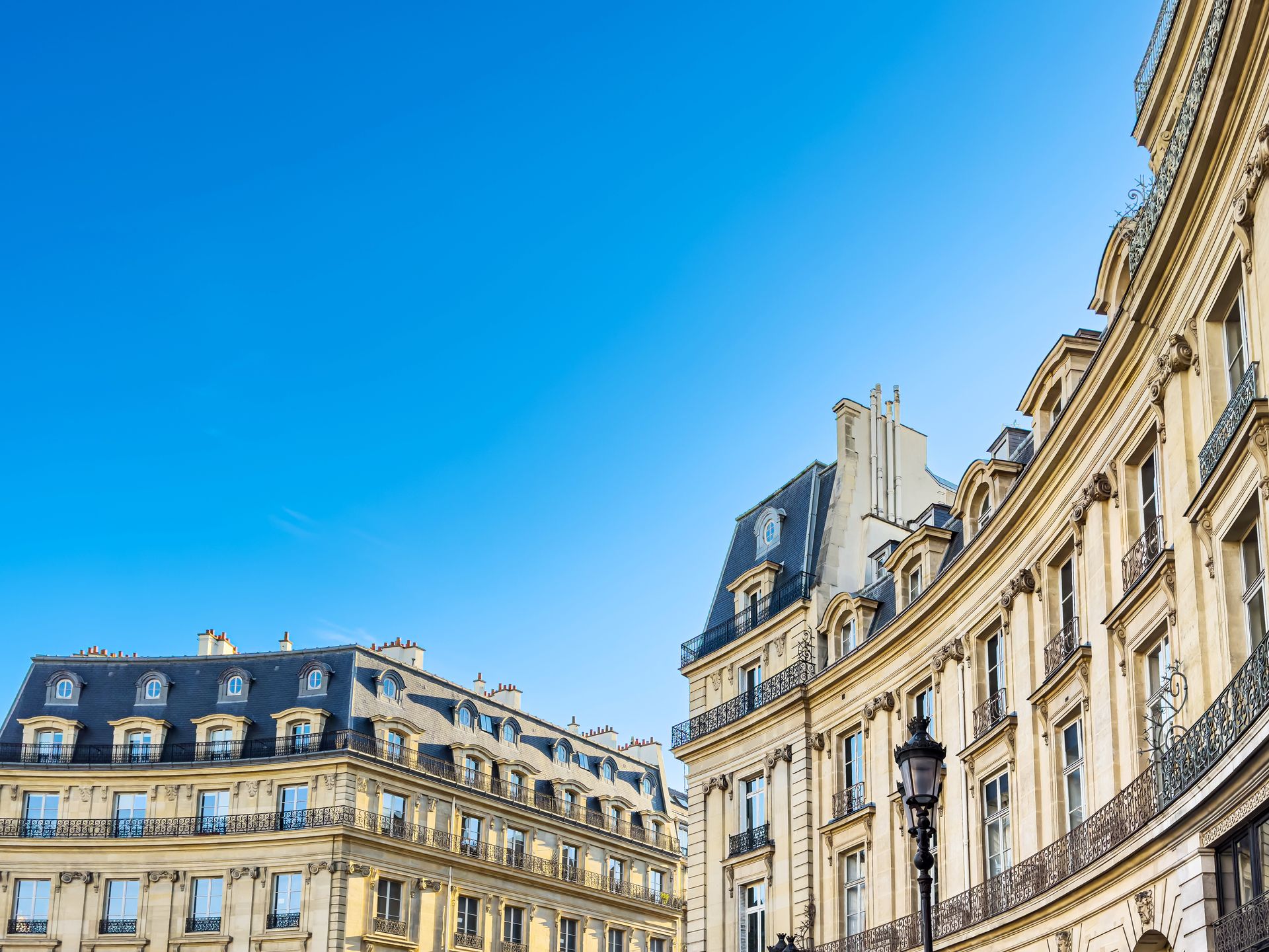Bâtiments parisiens historiques aux formes courbes et aux façades ornées, sous un ciel d'un bleu éclatant