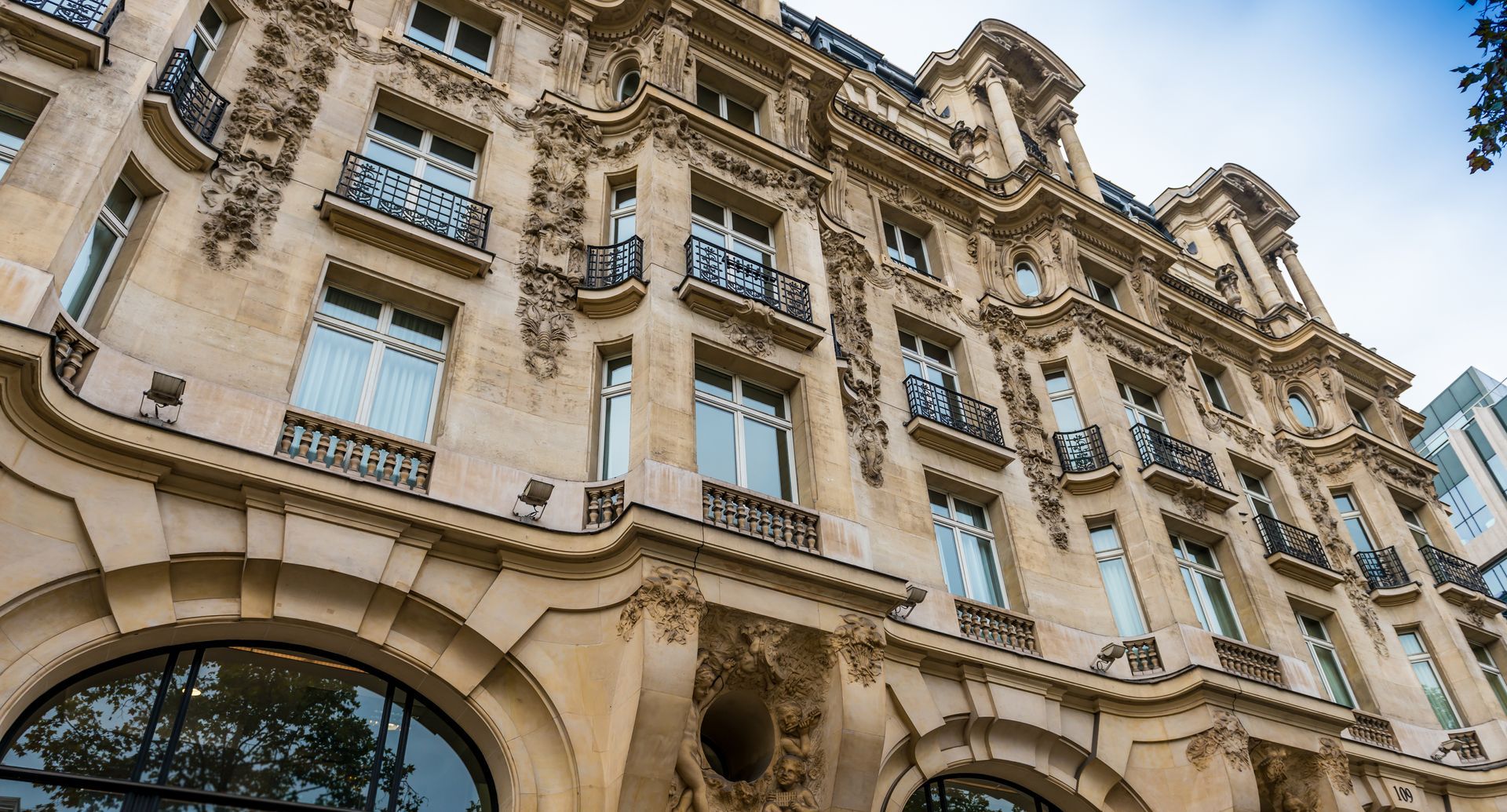 Façade historique beige ornée de fenêtres cintrées, vue d'en bas