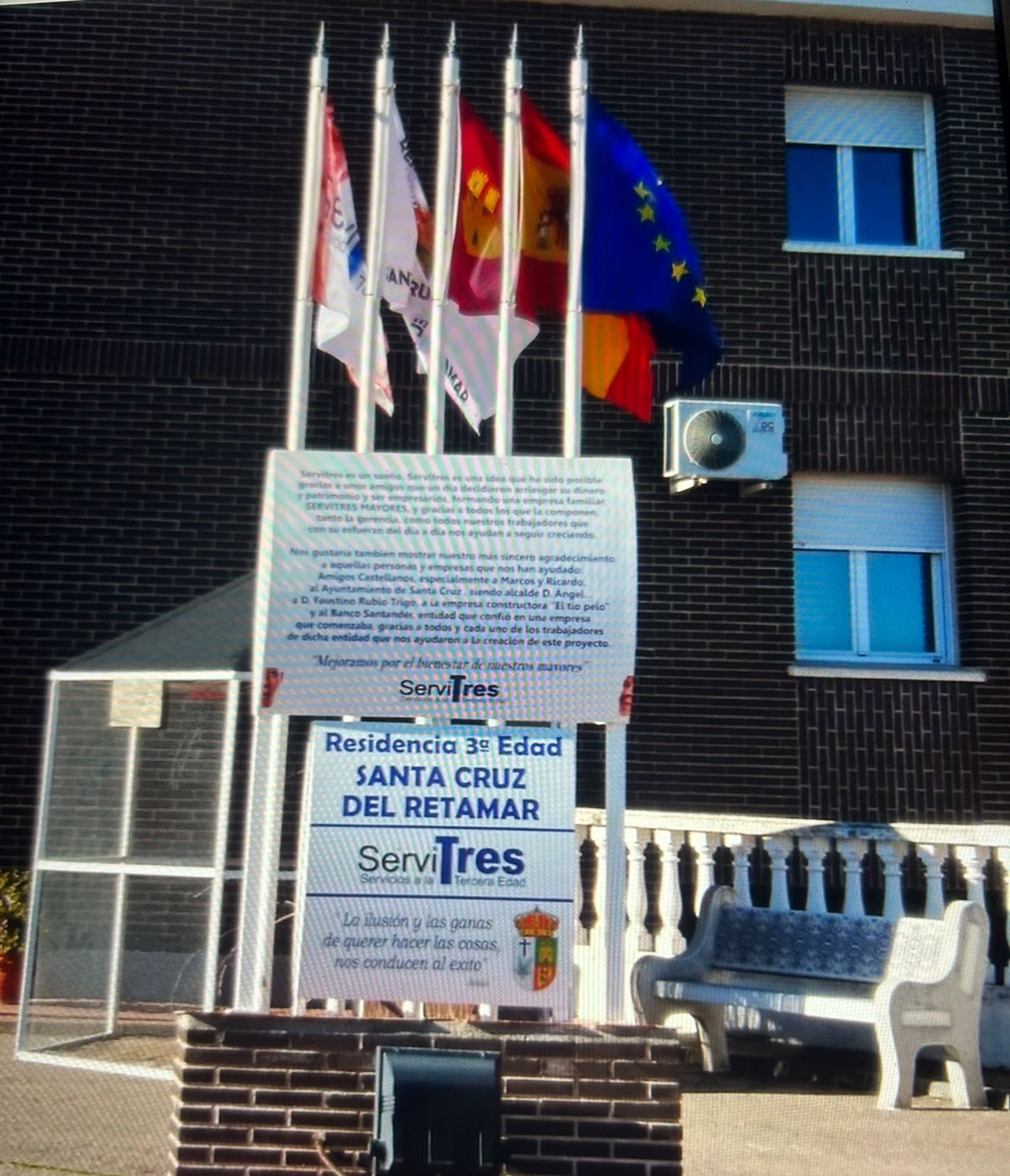 Entrada del edificio con banderas, cartel de residencia