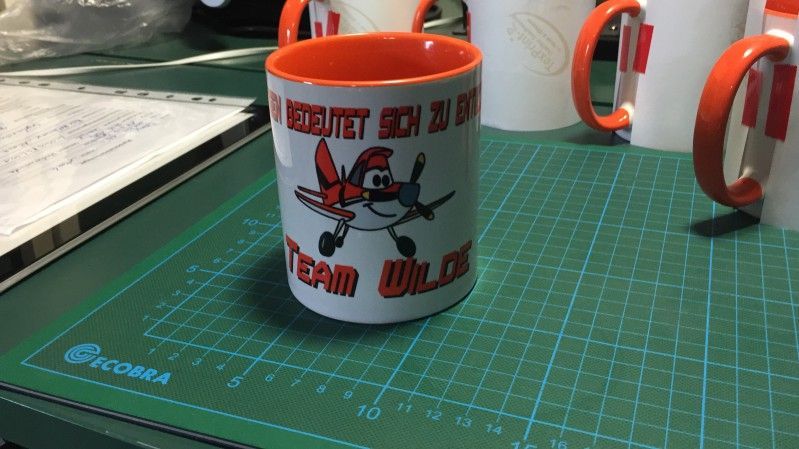 Auf einem Schneidebrett steht ein Becher mit einem Flugzeug darauf.