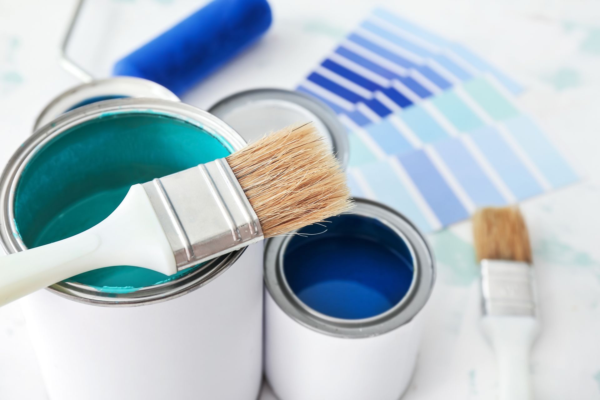 Des pots de peinture bleue et un pinceau.