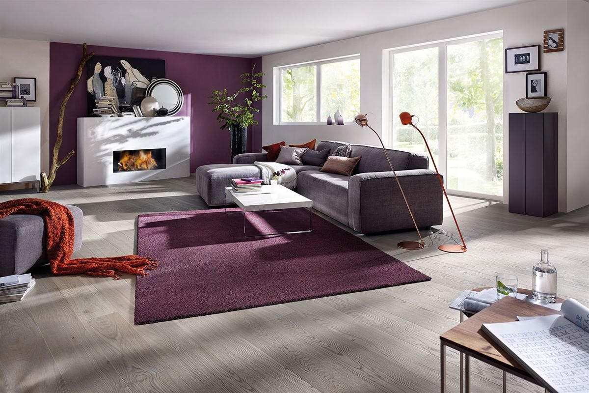 Ein Wohnzimmer mit einem lila Teppich und einem Kamin