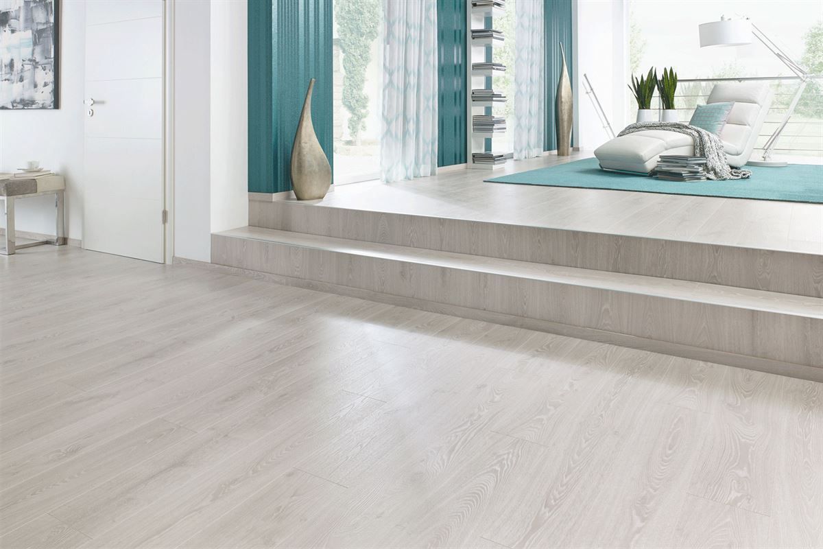 Ein Wohnzimmer mit weißem Holzboden und blauen Vorhängen.