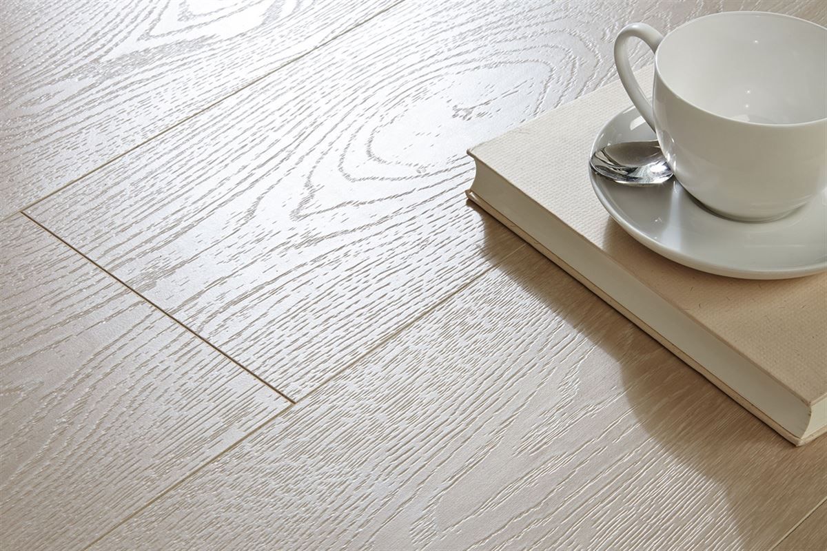 Eine Tasse Kaffee und ein Buch auf einer Untertasse auf einem Holzboden.