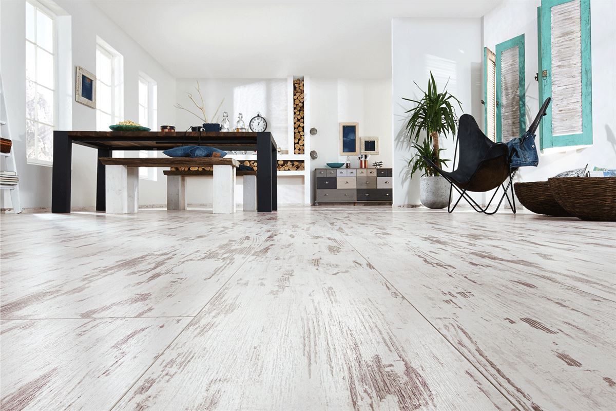 Ein Wohnzimmer mit Holzboden und einem Tisch und Stühlen.