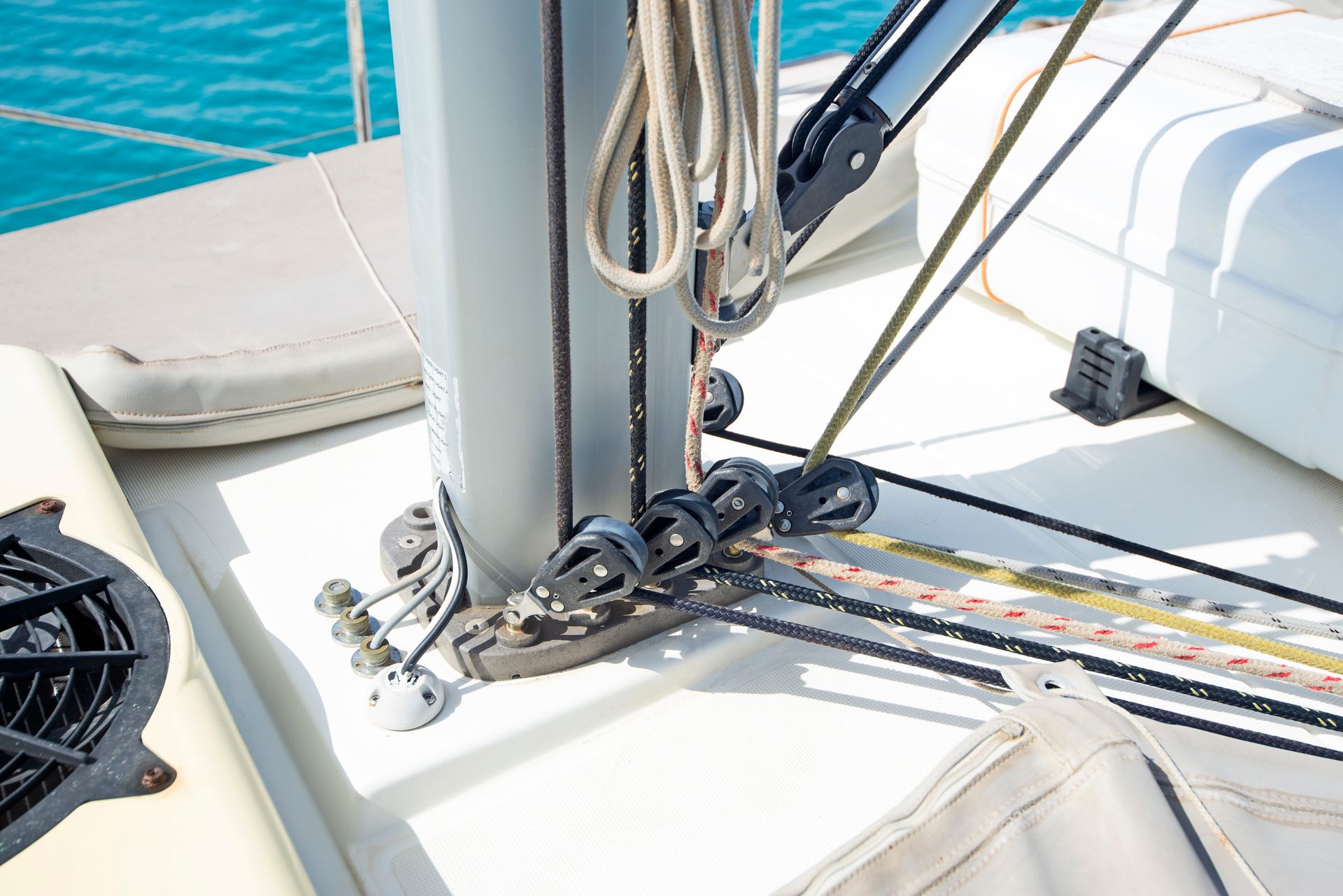 Gros plan sur la base d'un mât de voilier sur le pont, montrant les poulies, les cordages et les lignes fixés aux éléments de montage.