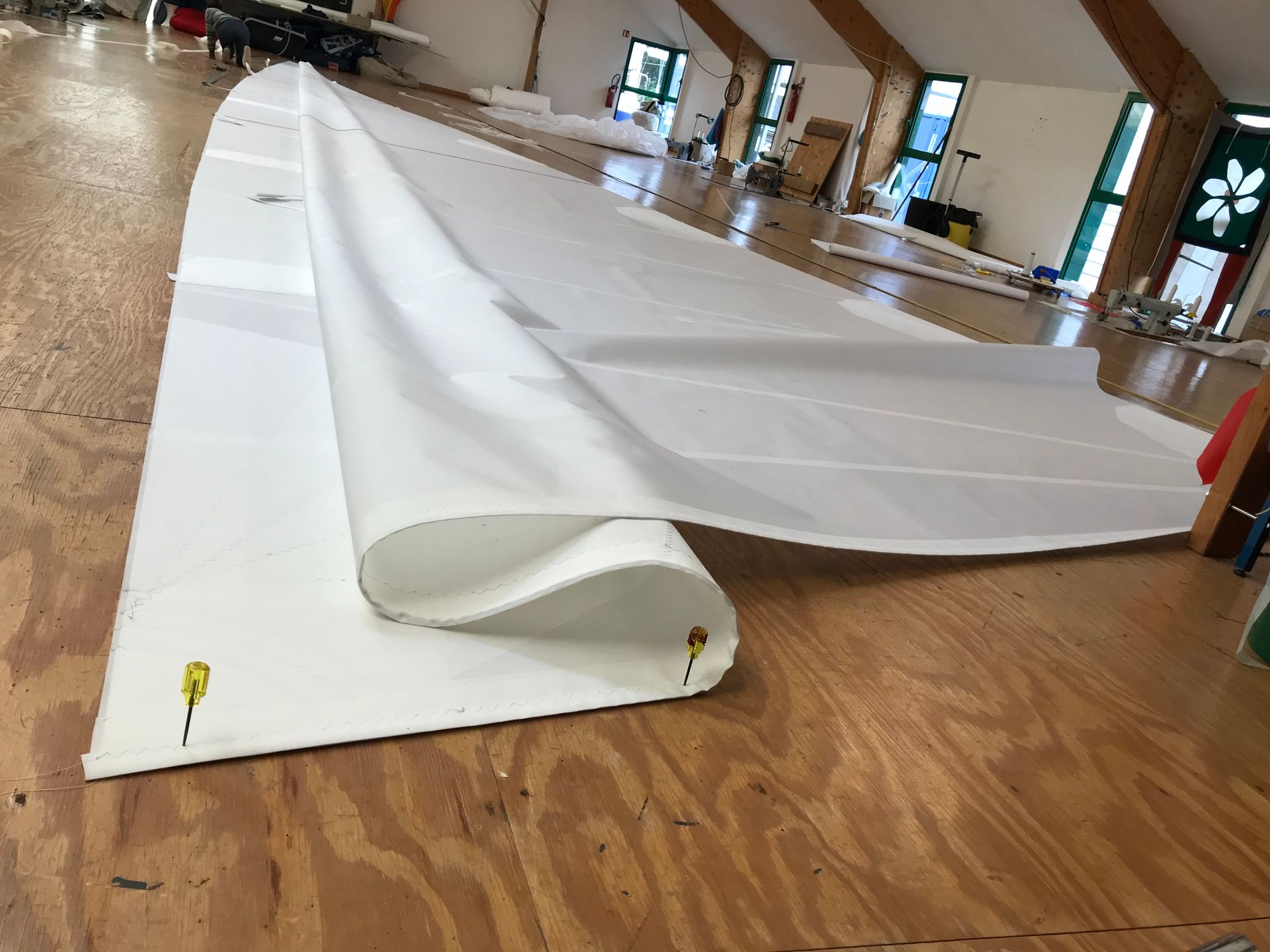 Un voilier blanc navigue sur une eau d'un bleu profond sous un ciel clair et lumineux, avec une côte lointaine visible en arrière-plan.