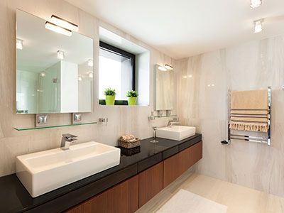 Baño moderno con dos lavabos, espejos, toallero y ventana.