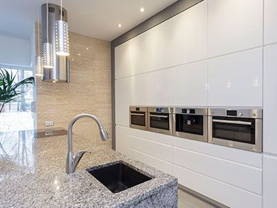 Cocina moderna con encimera de granito, electrodomésticos de acero inoxidable y gabinetes blancos.