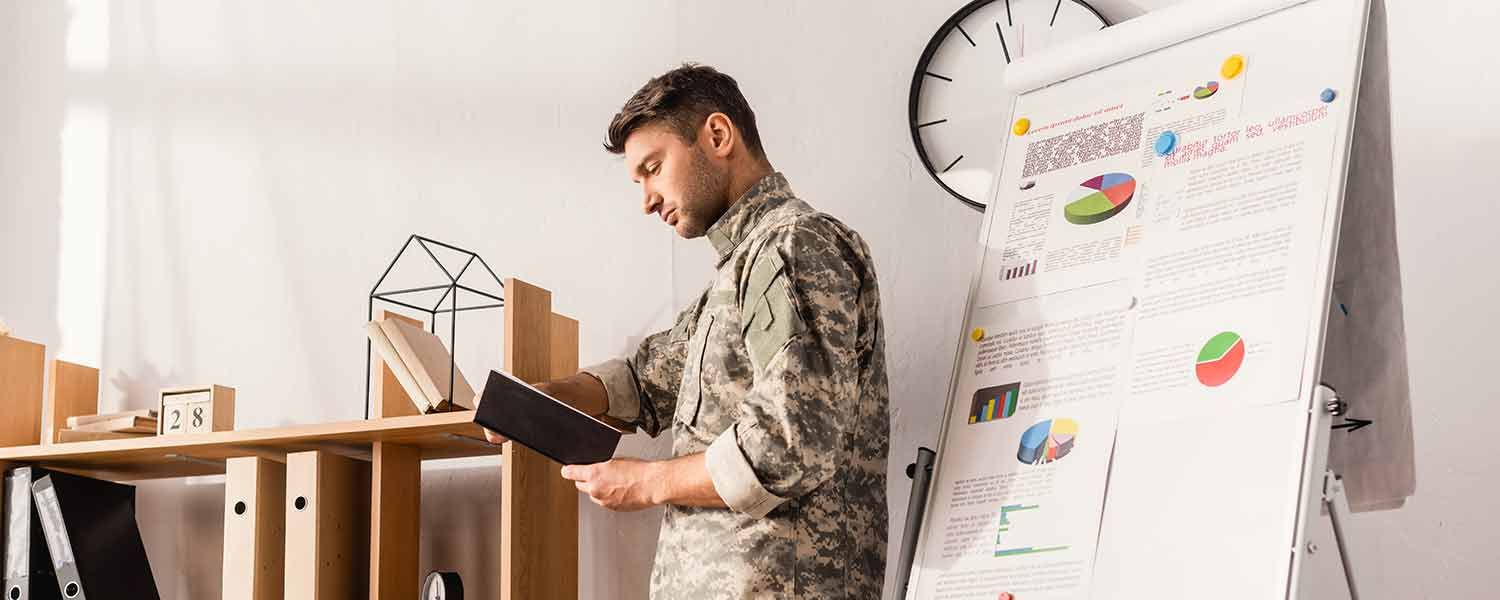 Ein Soldat steht vor einem Flipchart und benutzt ein Tablet .