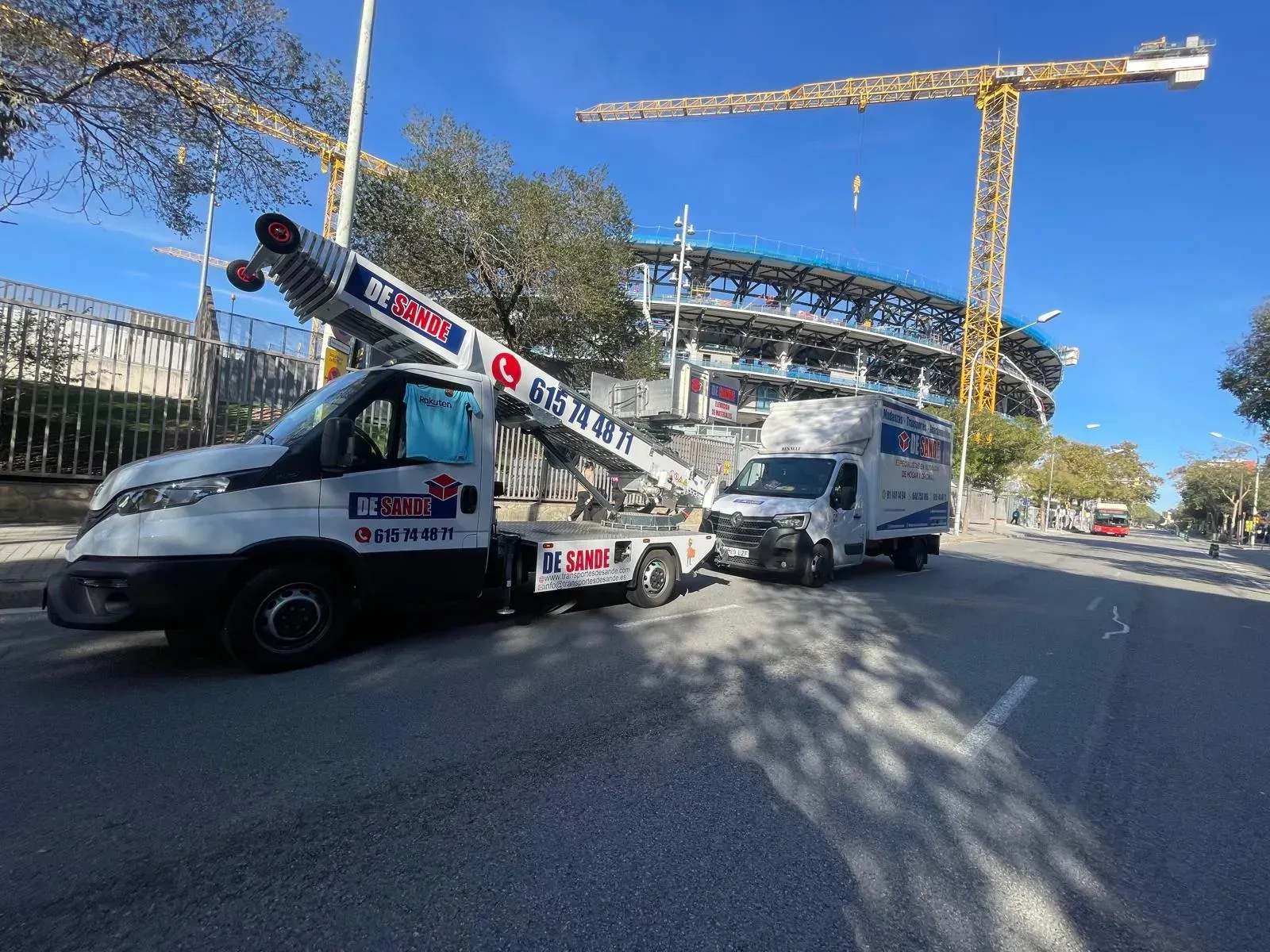 Un camión blanco con una escalera extensible, otro camión blanco y grúas de construcción.