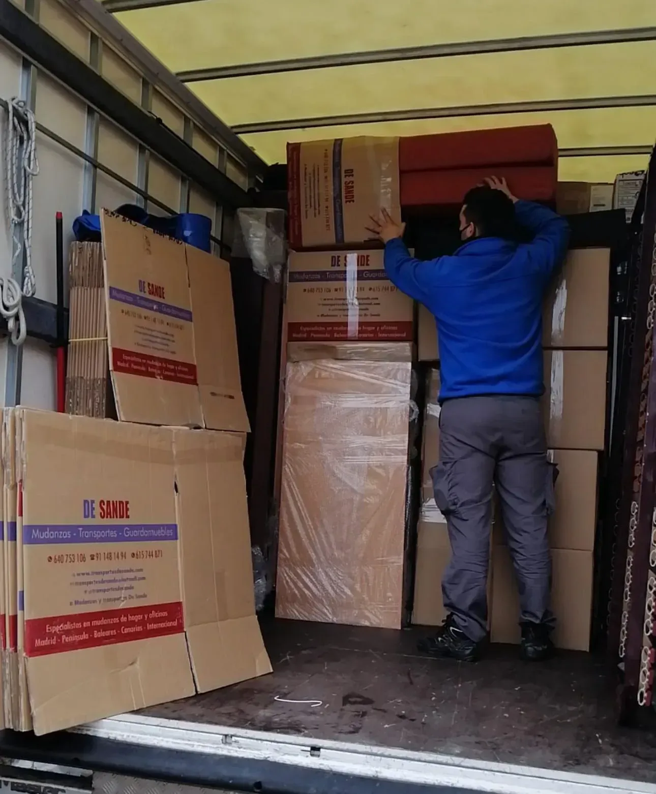 Cajas de cartón apiladas dentro de una furgoneta de carga, listas para su transporte.