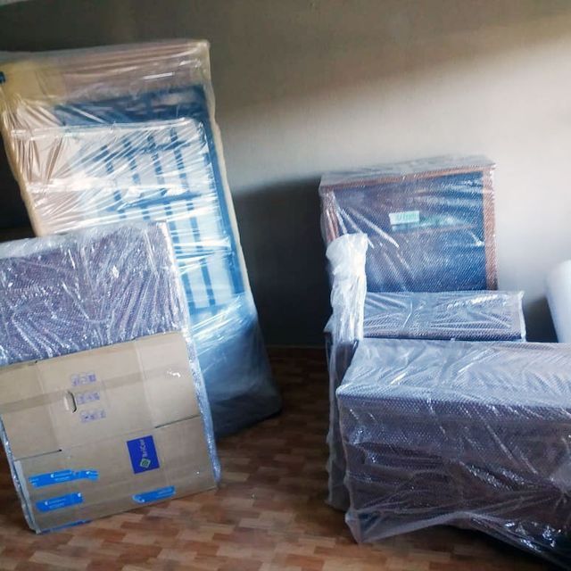 Muebles envueltos en plástico, listos para ser trasladados, apoyados contra una pared en el interior.
