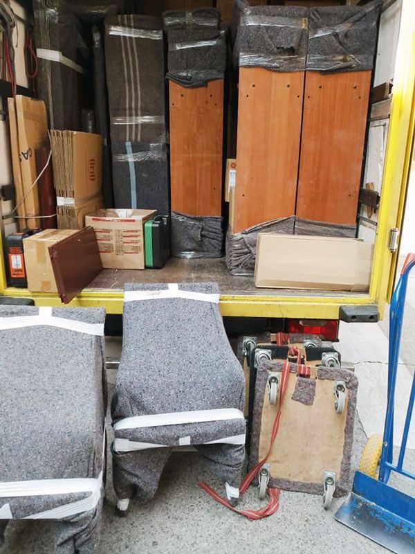 La caja de una camioneta estaba llena de muebles y cajas, incluyendo sillas envueltas y piezas altas de madera.