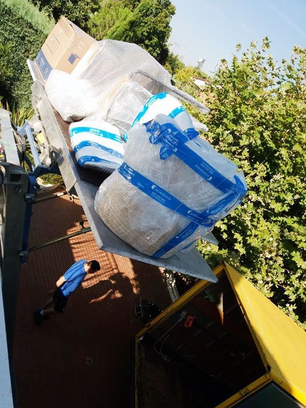 Cajas y artículos envueltos en un ascensor; persona con camisa azul mirando hacia arriba.