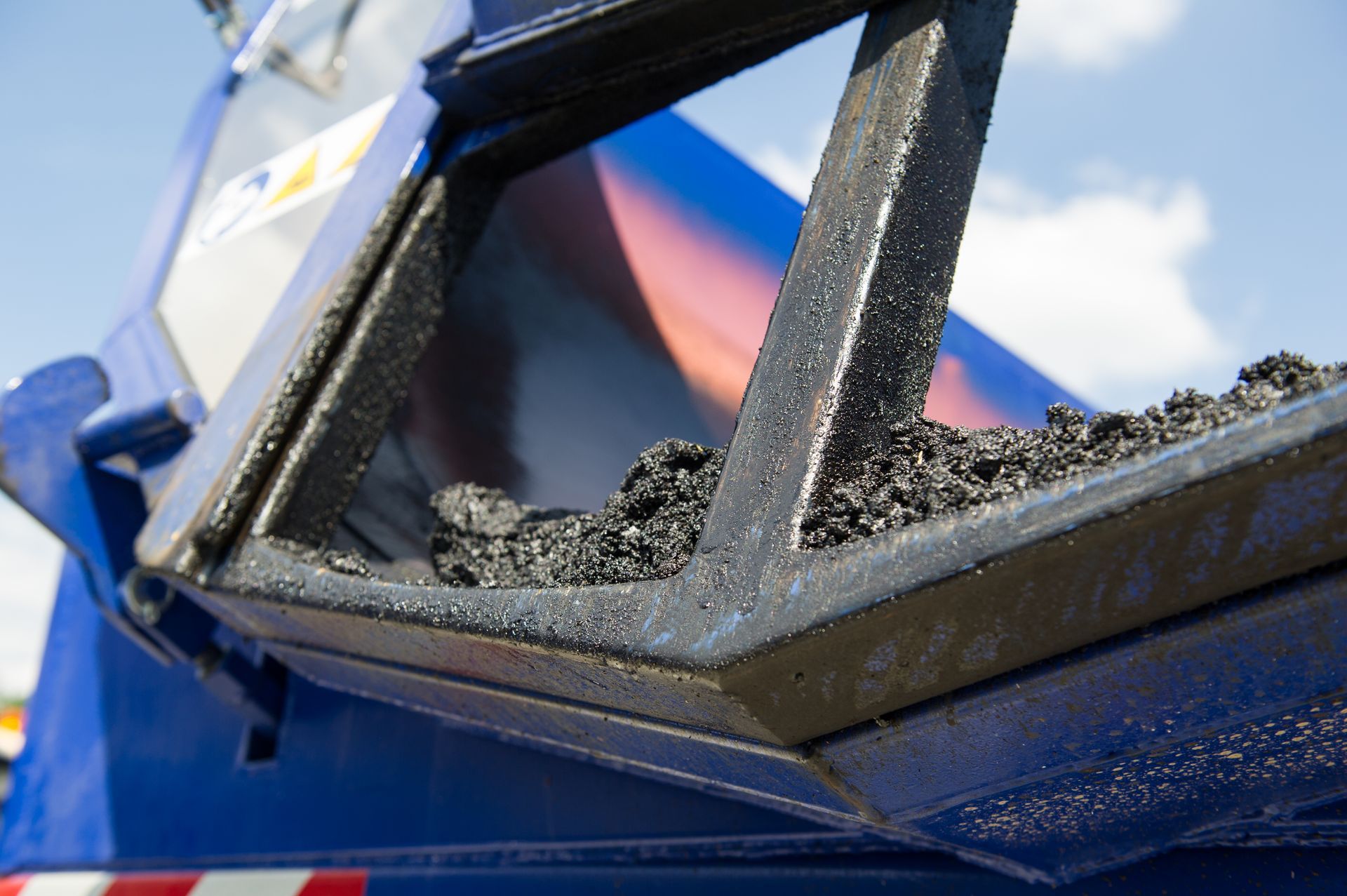 Ein Bauarbeiter benutzt ein Vermessungsinstrument auf einer Baustelle. Weitere Arbeiter in Warnwesten und Schutzhelmen sind zu sehen.