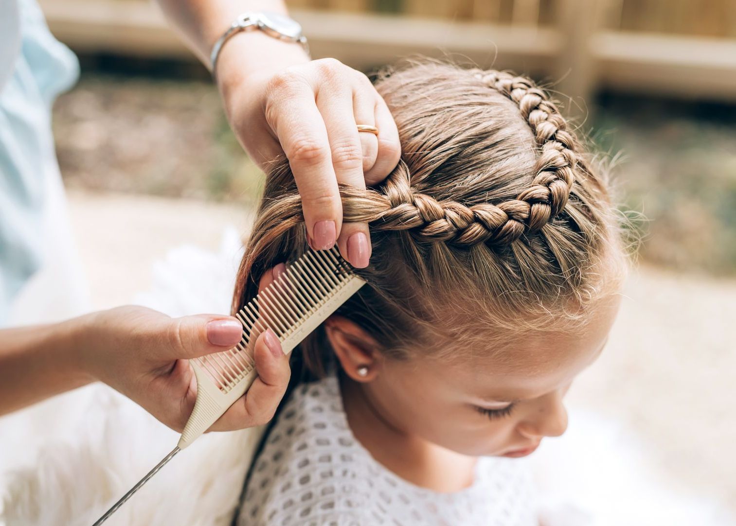 Eine Frau kämmt einem kleinen Mädchen mit einem Kamm die Haare.