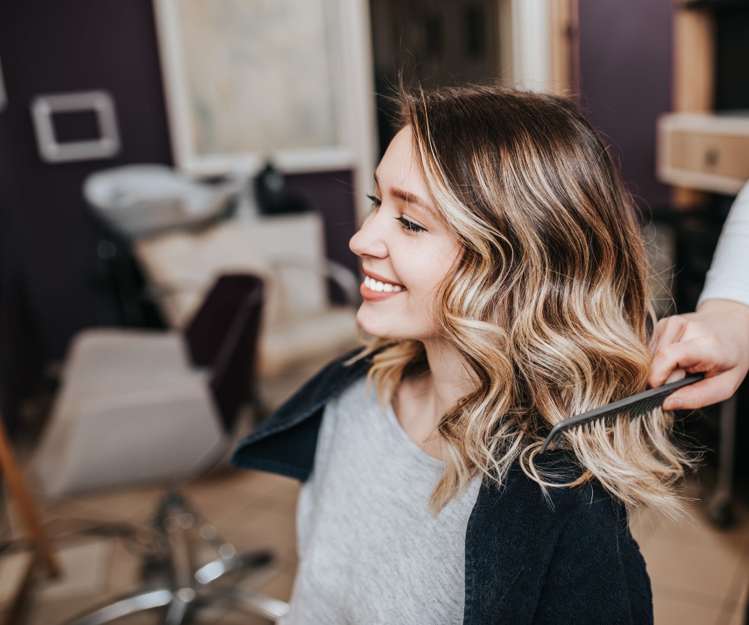 Eine Frau lässt sich in einem Salon von einem Friseur die Haare machen.
