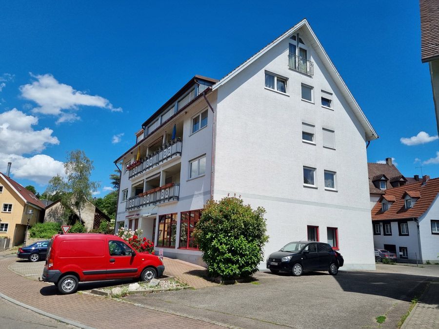 Ein weißes Gebäude mit einem davor geparkten roten Lieferwagen