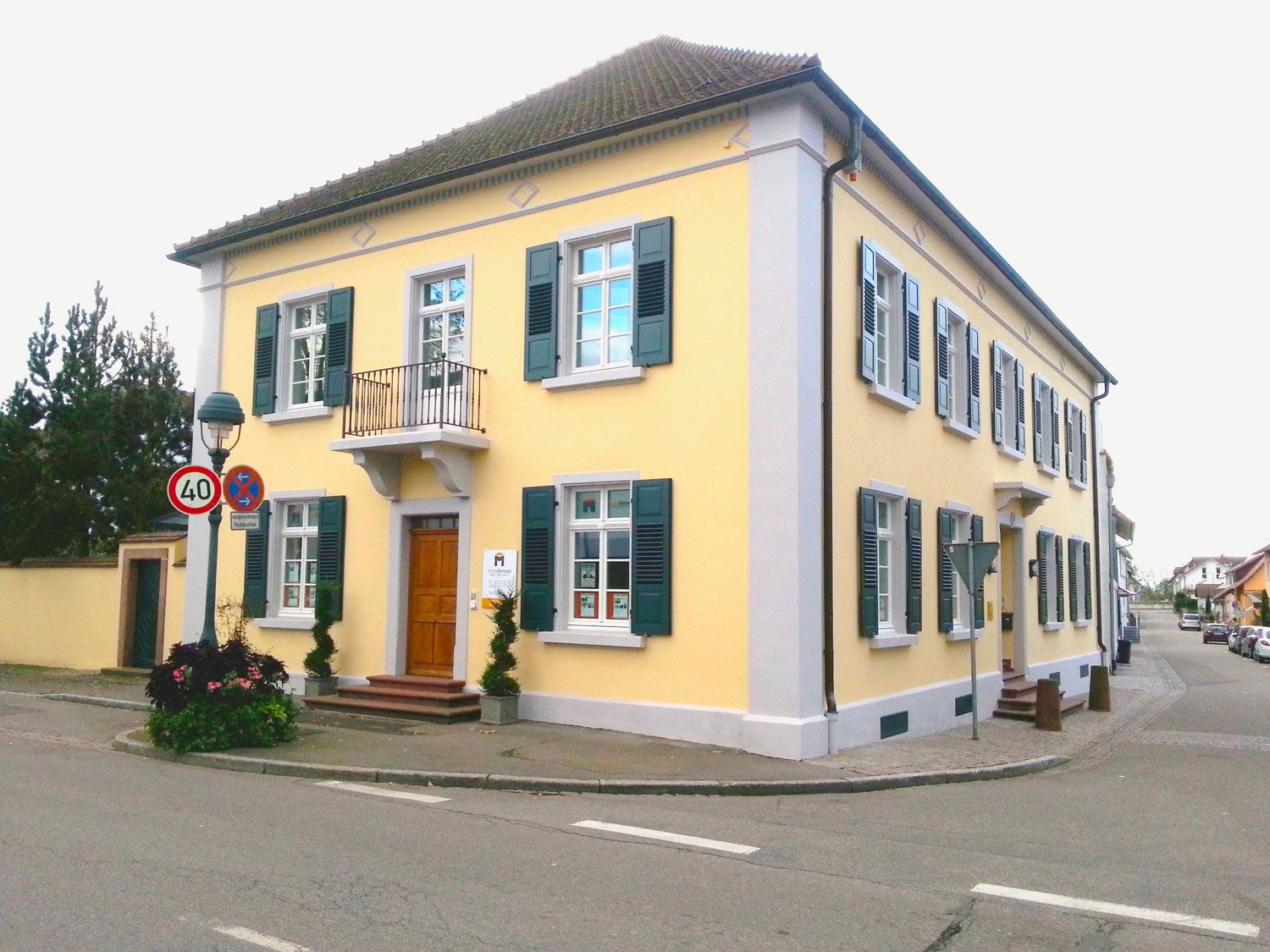 Ein gelbes Gebäude mit grünen Fensterläden steht an der Ecke einer Straße