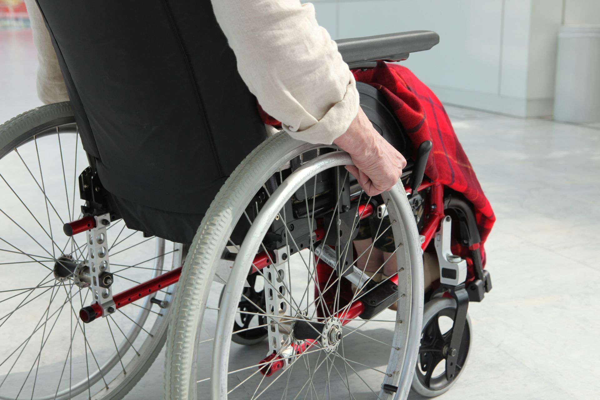 Une personne pousse un fauteuil roulant dans les couloirs d'un hôpital.