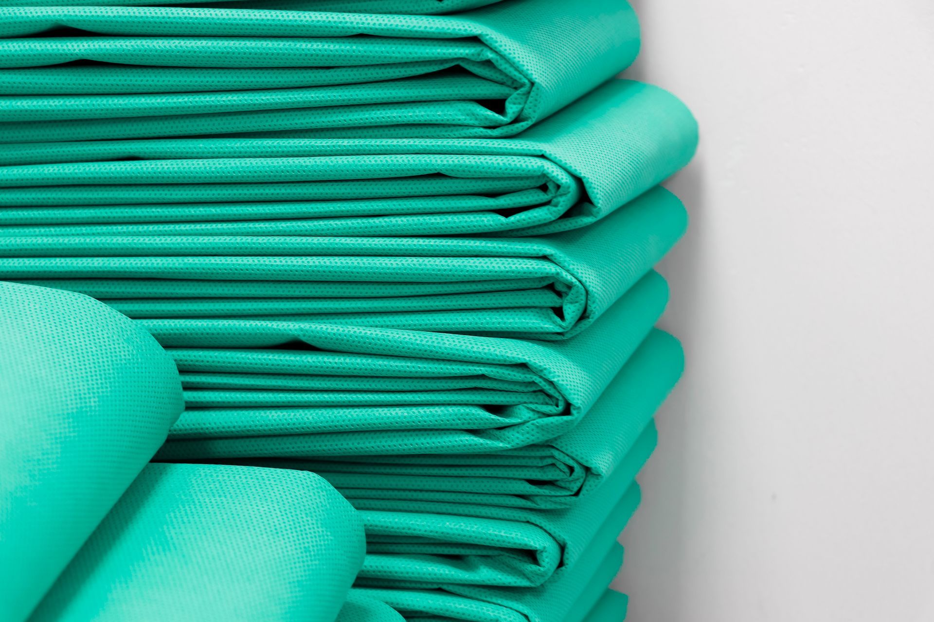Blouses d'hôpital turquoise pliées et soigneusement rangées.