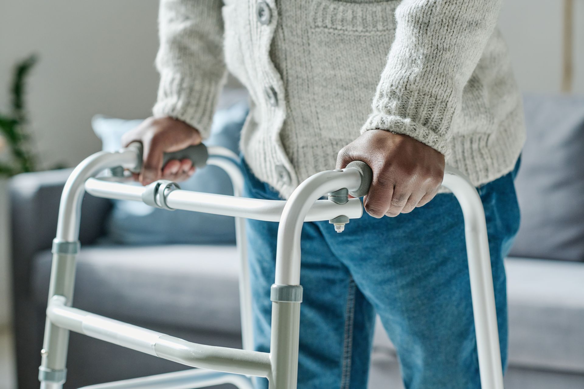 Une personne tenant un déambulateur blanc dans un salon.