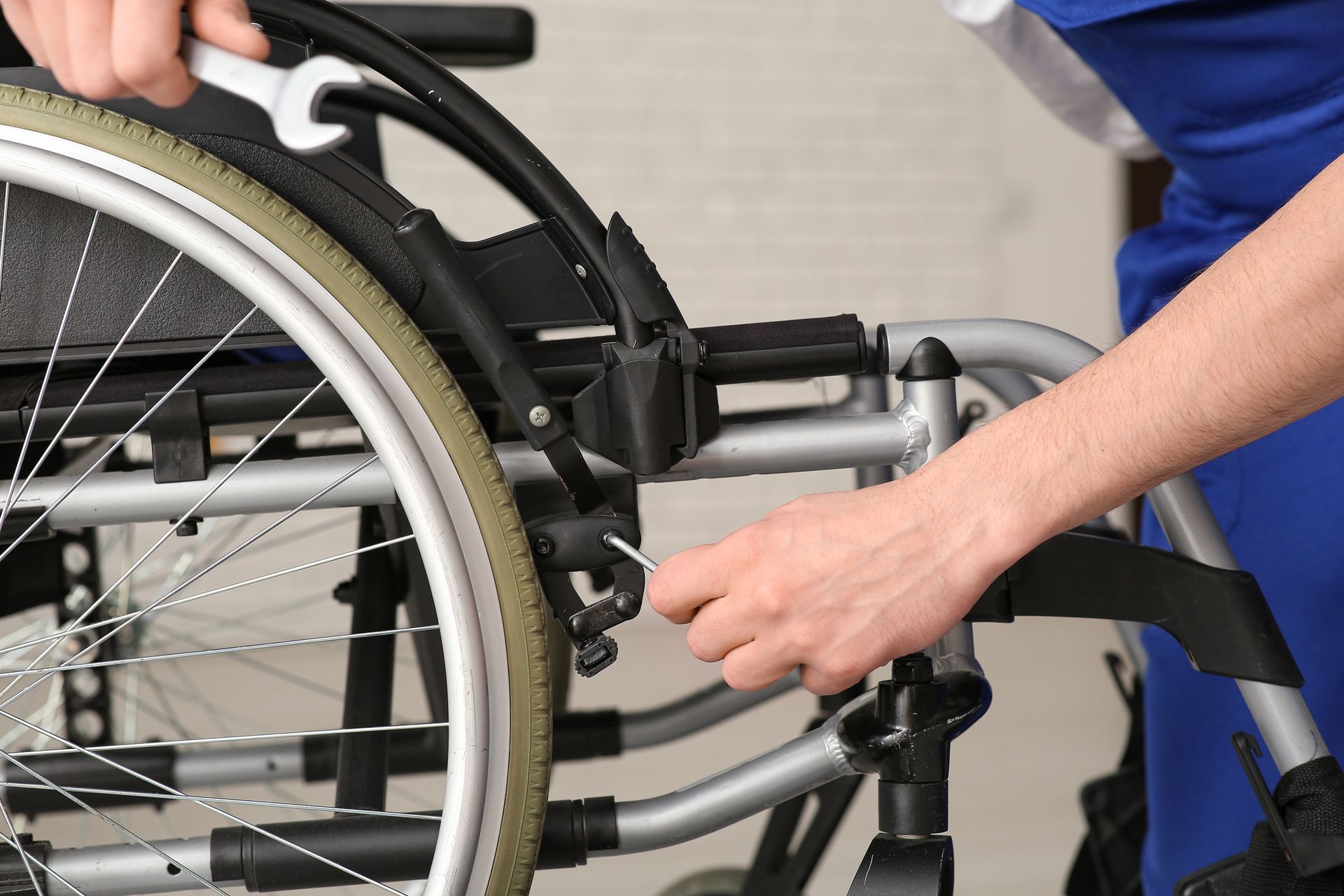 Des mains ajustent une roue et un cadre de fauteuil roulant.