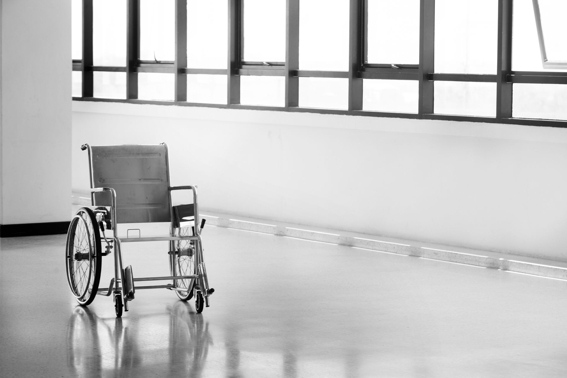 Fauteuil roulant manuel gris dans un couloir lumineux.