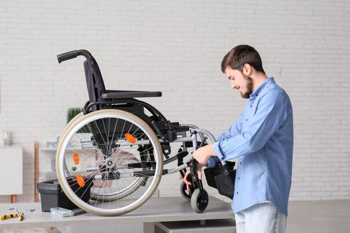 Un homme ajuste un fauteuil roulant dans une pièce lumineuse.