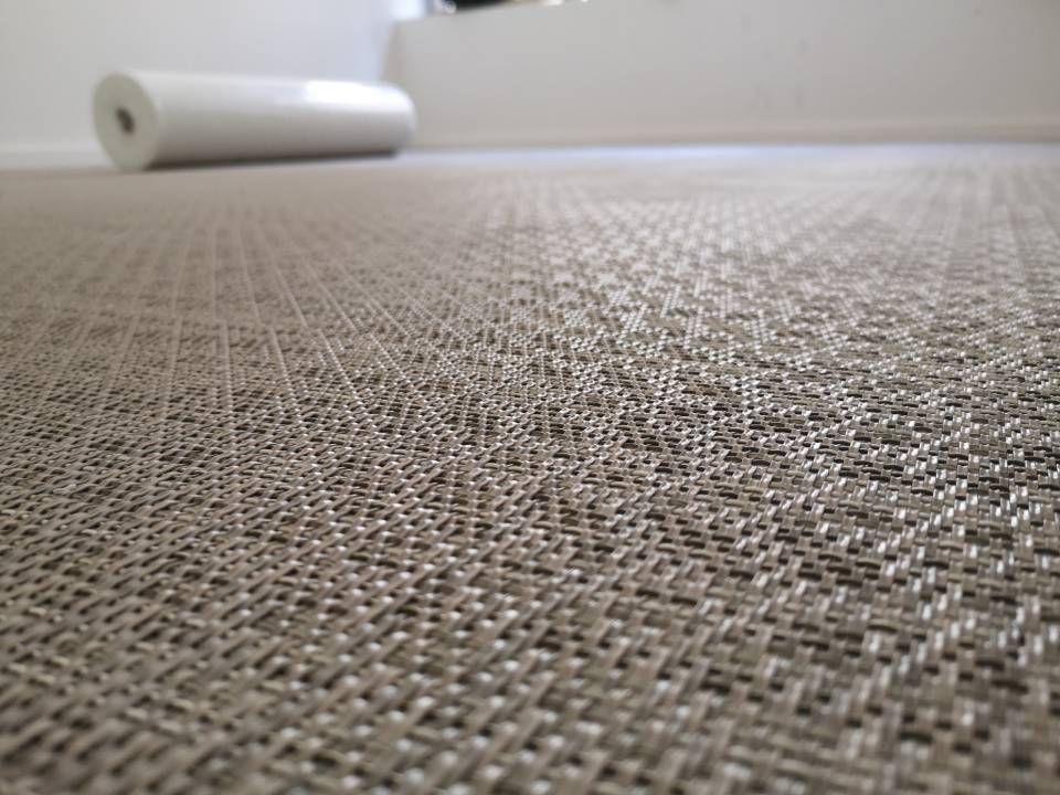 Un rouleau de papier peint est déroulé sur un sol recouvert de moquette.