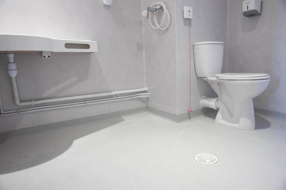 Une salle de bain avec WC, lavabo et évacuation.