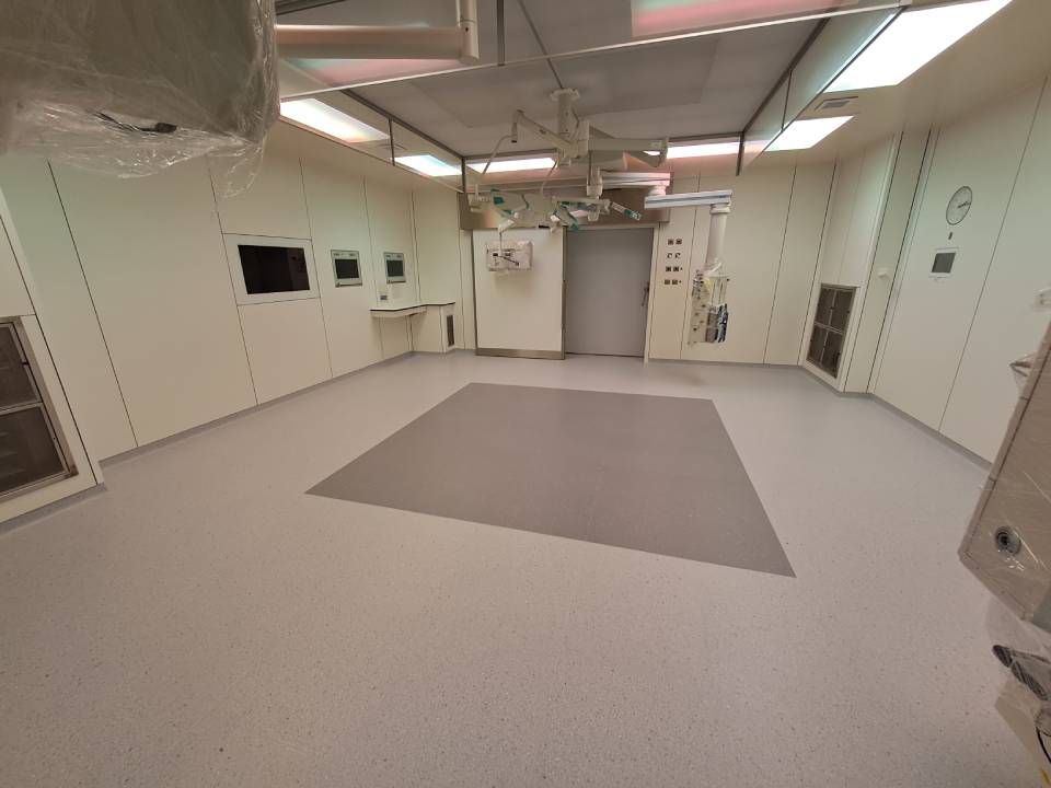 Une salle d'opération vide dans un hôpital avec un tapis carré sur le sol.