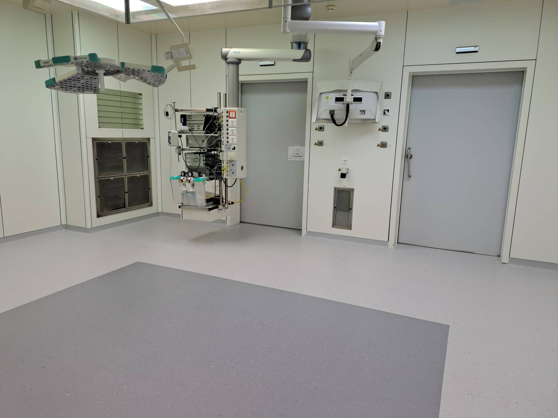 Une salle d'opération vide avec un sol gris et des murs blancs