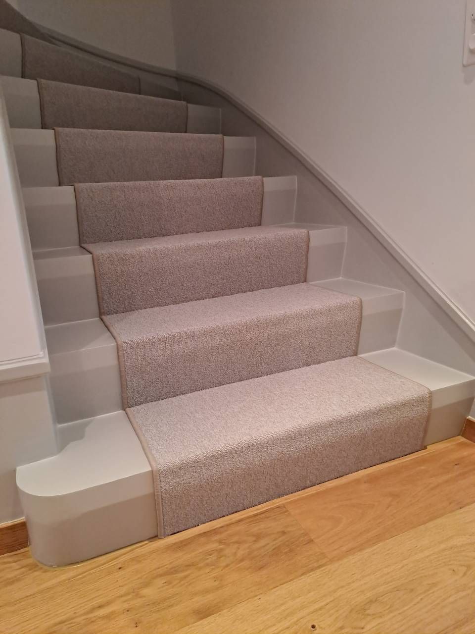 Un escalier avec un tapis sur les marches et un plancher en bois.